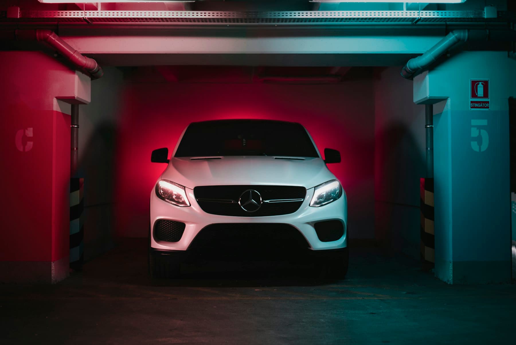 White Mercedes-Benz parked in a garage bay lit with red light
