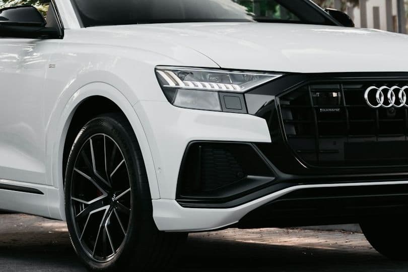 Close detail of the white Audi Q8 headlight, grille and wheel