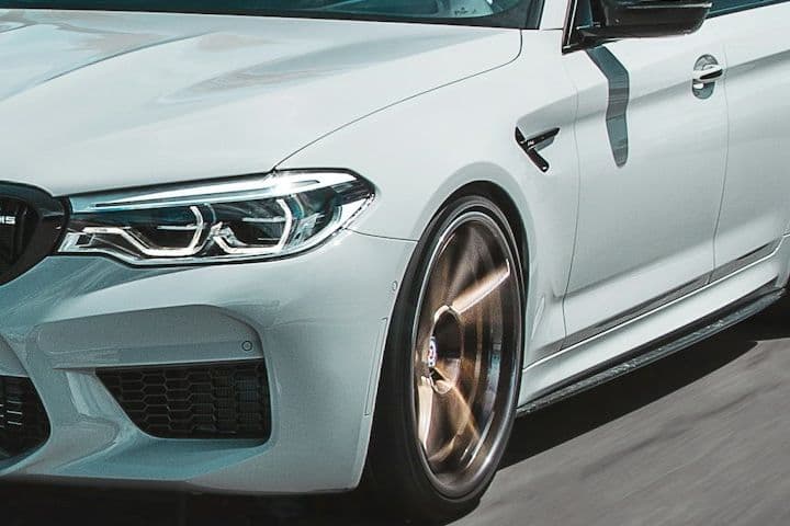 Front wheel and headlight detail of the white BMW M5