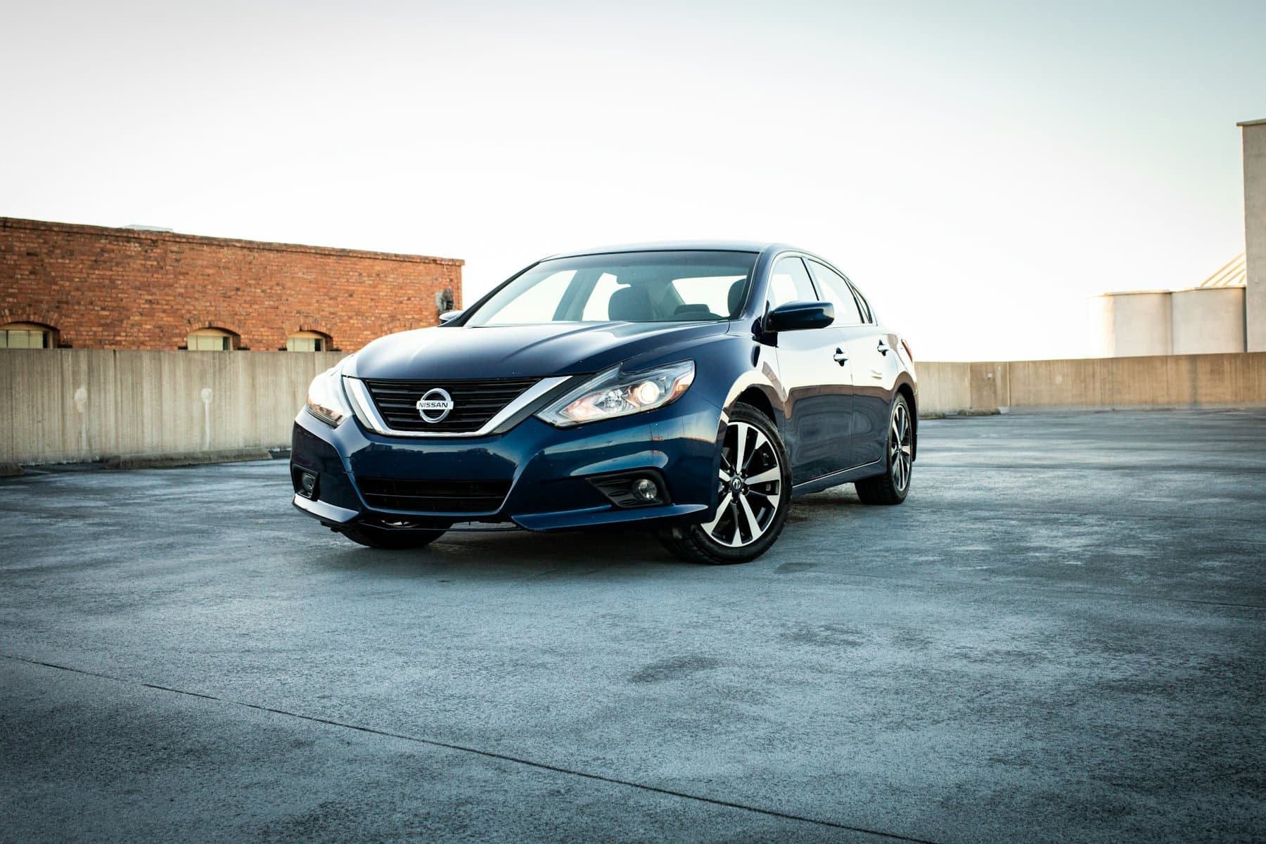 Dark blue Nissan Altima sedan parked on a wet car park