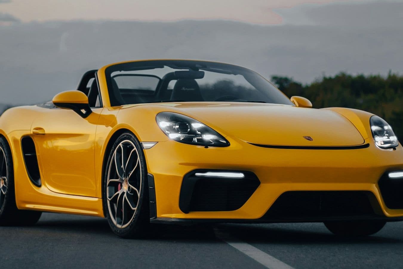Front three-quarter view of the yellow Porsche 718 Spyder with its roof stowed