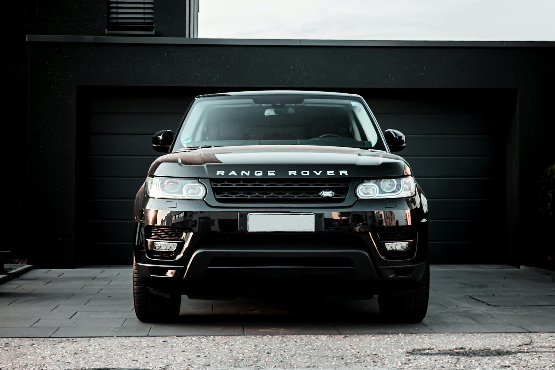 Black Range Rover Sport parked in front of a dark garage door