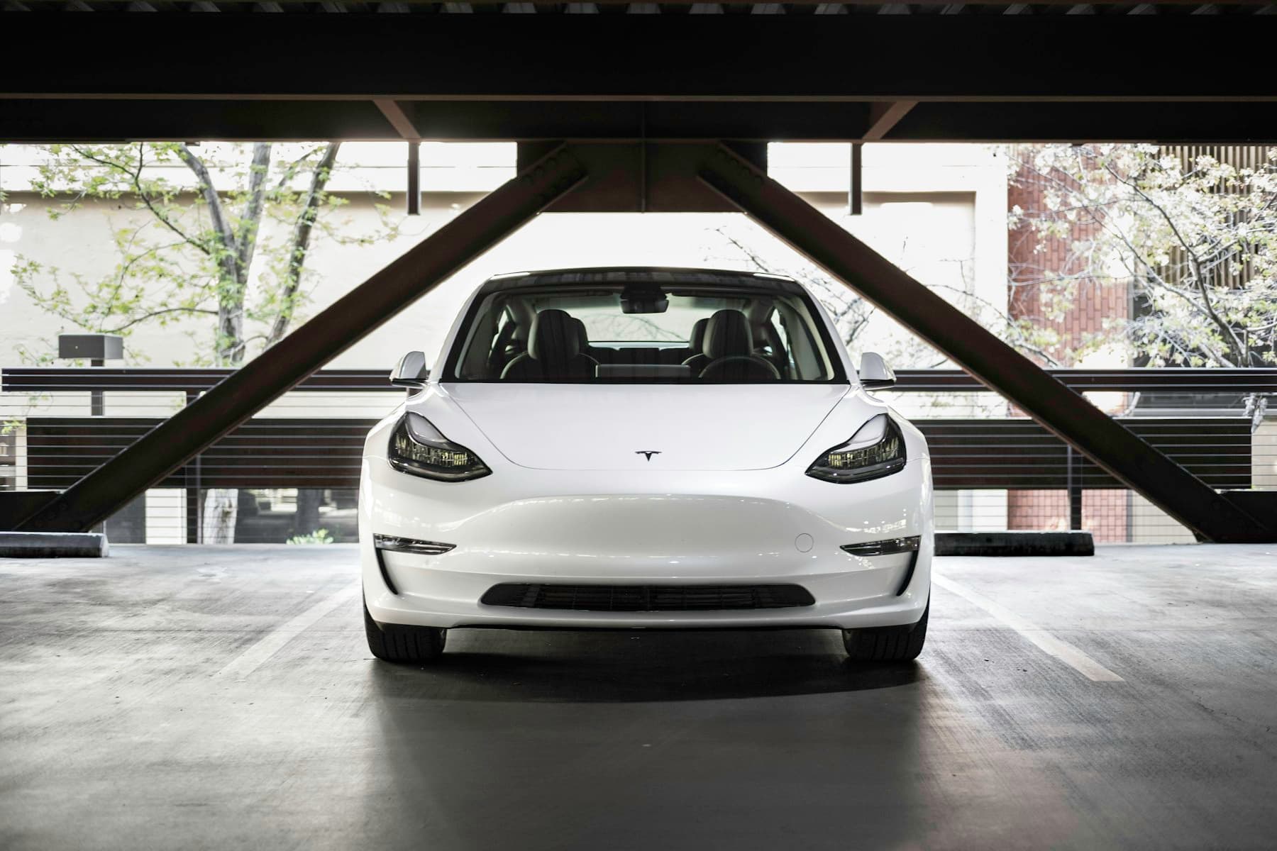 White Tesla Model 3 seen head-on beneath a concrete canopy