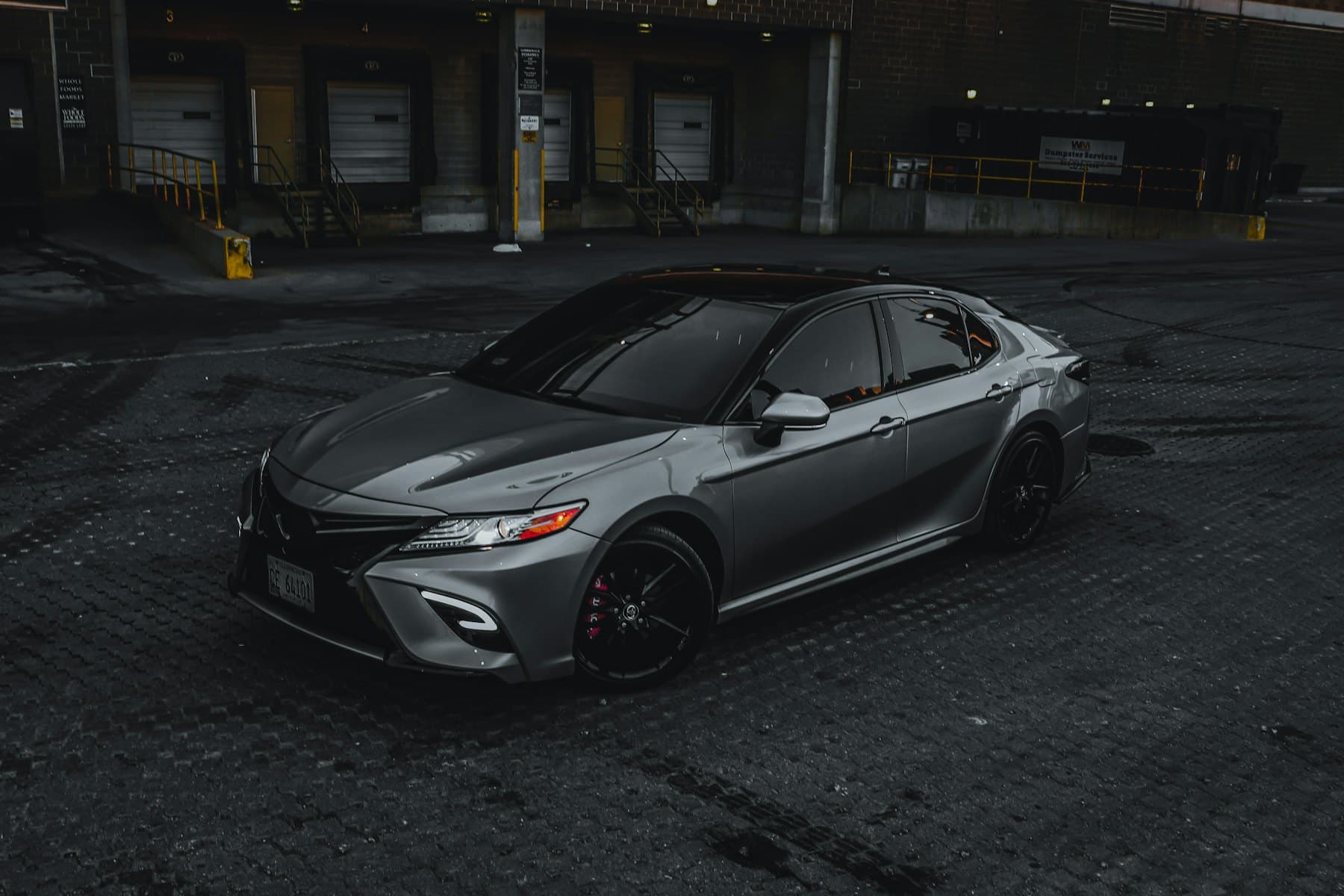 Grey Toyota Camry sedan parked on dark paving at night