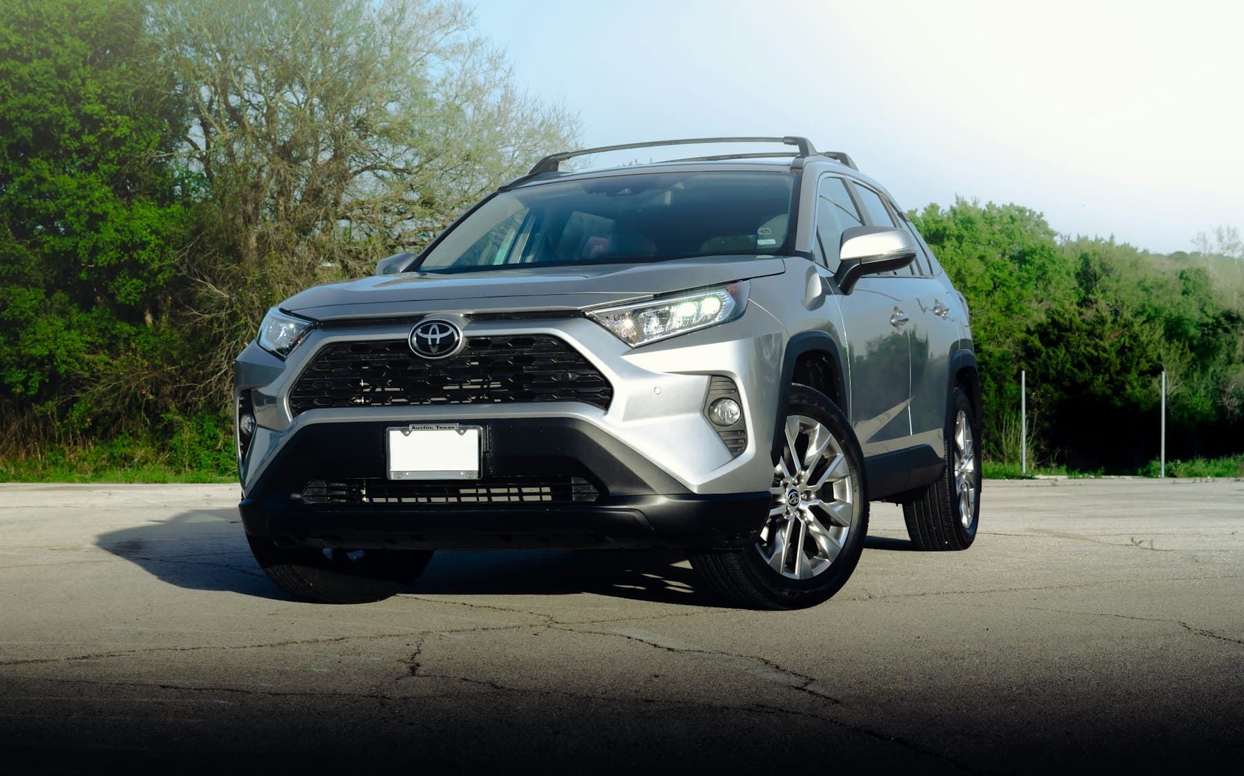 Silver Toyota RAV4 parked in a car park with trees behind