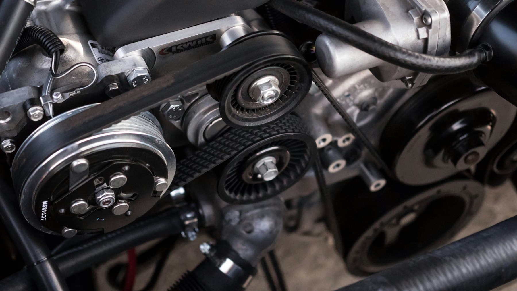 Close view of an engine bay showing belts, pulleys and the alternator