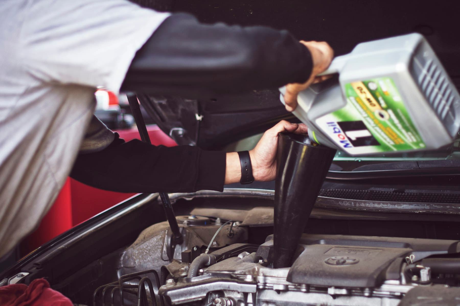 Technician pouring fresh engine oil during a service
