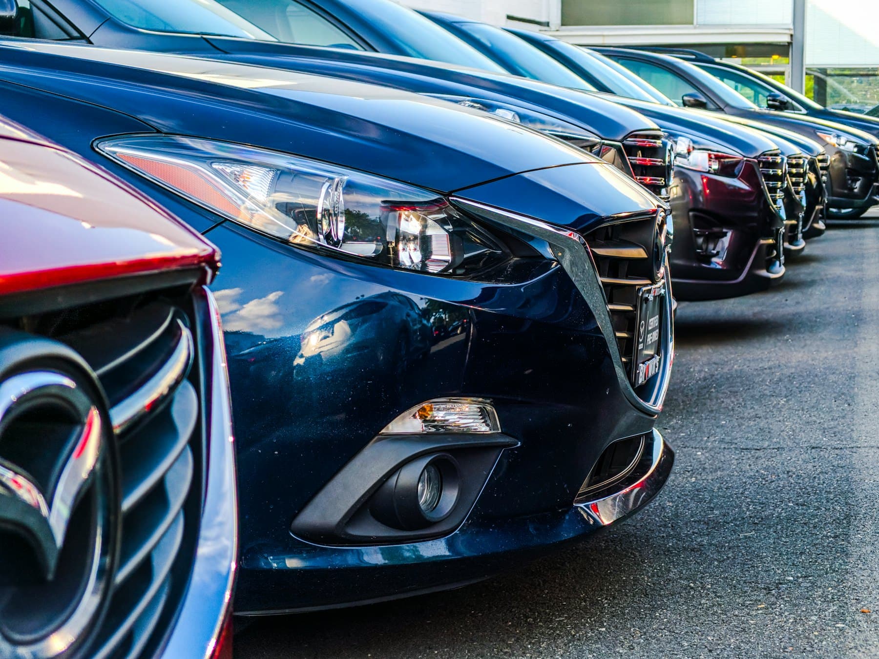 A row of polished cars parked side by side, seen close to the front grilles